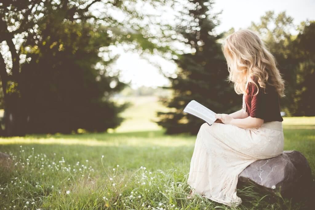 Woman reading book outside | Take charge of your own mental health